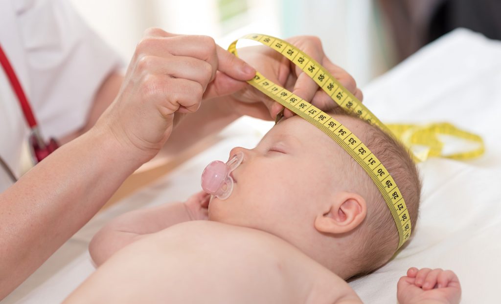 Lekárka meria obvod hlavy novorodenca